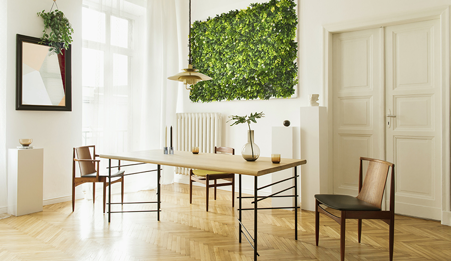 How to make artificial plants look real 4 Stylish and modern dining room interior with design sharing table, chairs, gold pedant lamp, abstract paintings and elegant accessories. Tropical leafs in vase. Eclectic decor. Brown wooden parquet.